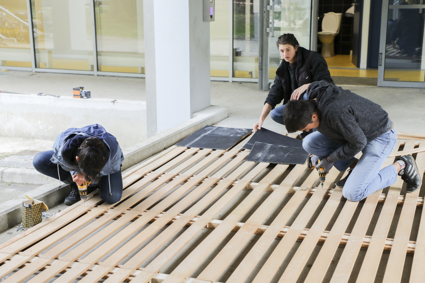 Les étudiantes et étudiants en action sur le chantier de construction en matériaux de réemploi devant le bâtiment Bergès sur le domaine universitaire.