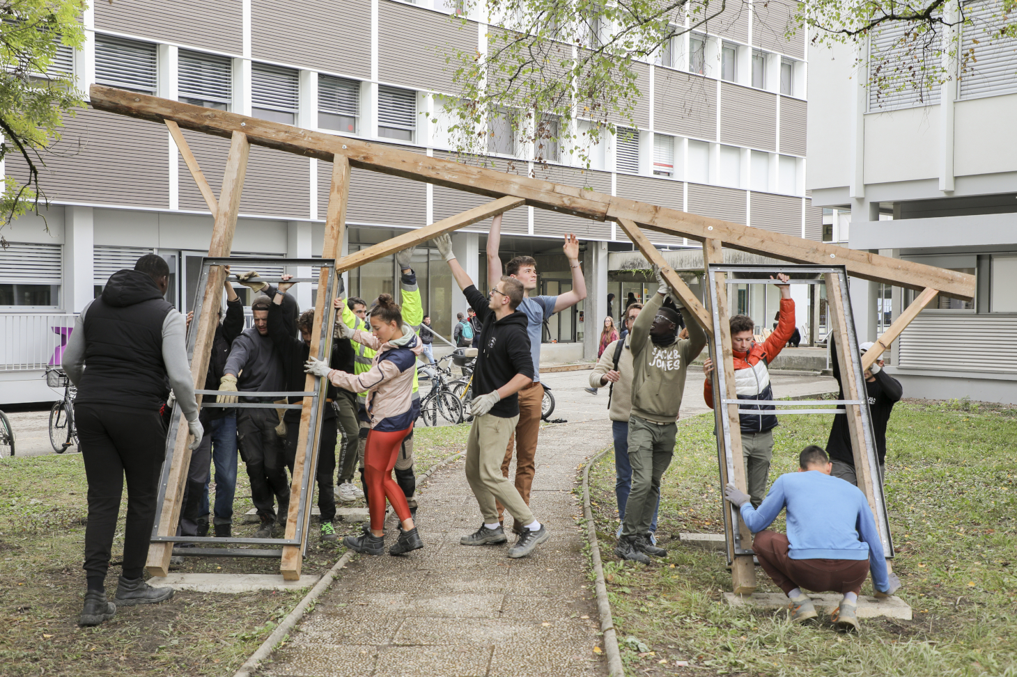 Les étudiantes et étudiants en action sur le chantier de construction en matériaux de réemploi devant le bâtiment Bergès sur le domaine universitaire.